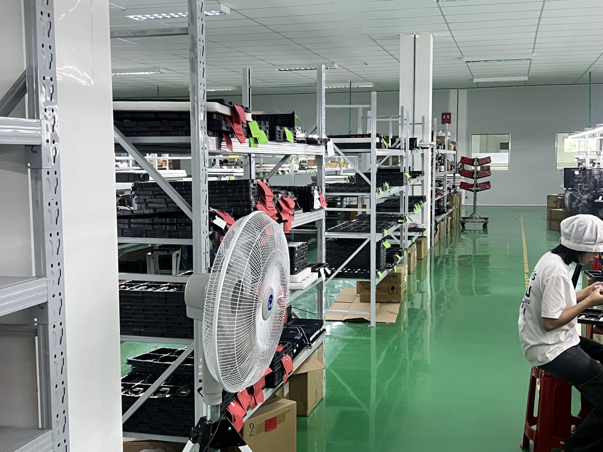 Manual assembly line with workers at workstations in clean-room coats