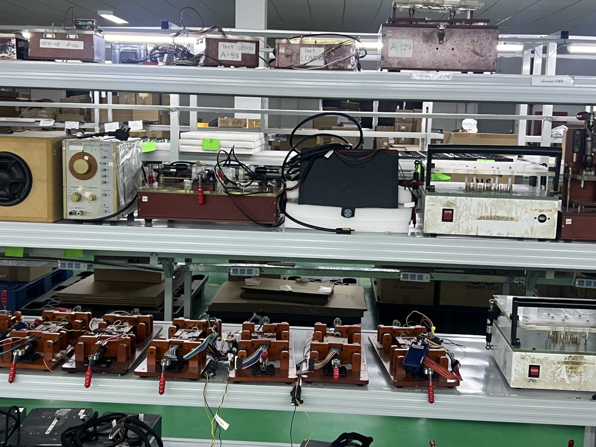 Industrial test jig rack with numbered per-product fixtures and PCBA test connectors